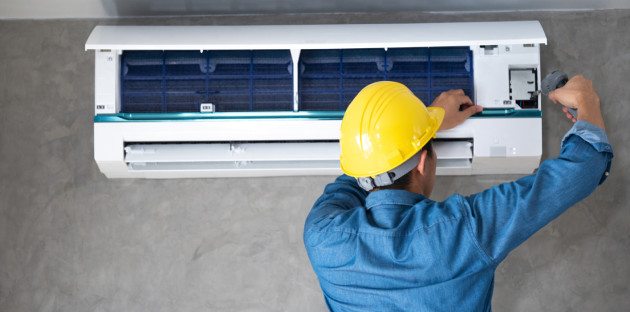 Technicien en train d’ouvrir une unité intérieure de climatisation pour réaliser l’entretien et le nettoyage du système de climatisation.