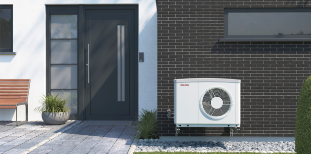 Pompe à chaleur extérieure blanche installée contre la façade d’une maison contemporaine, près de la porte d’entrée.