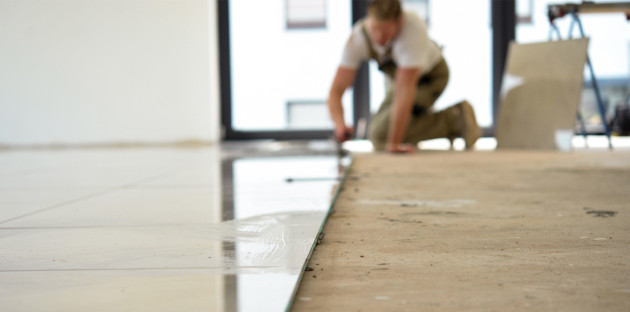 Homme qui pose des carreaux de carrelage grand format au sol