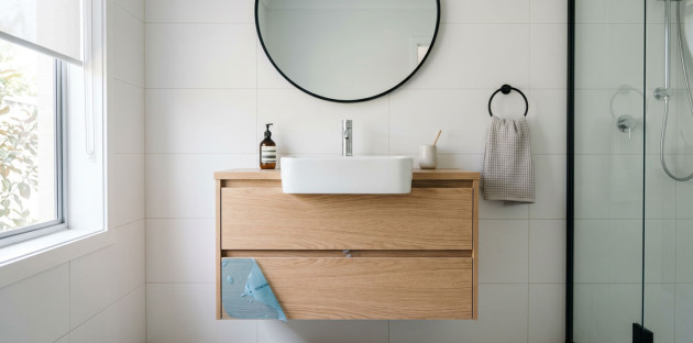 Meuble de salle de bains suspendu en bois avec vasque à poser et grand miroir rond.