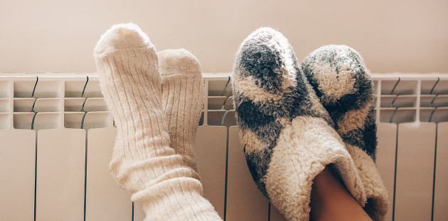 Deux personnes qui posent leurs pieds avec des chaussettes en laine contre un radiateur