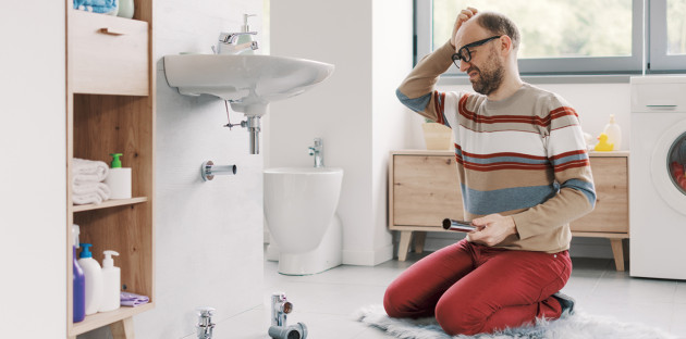 Particulier confronté au démontage de la plomberie d’un lavabo dans une salle de bains.