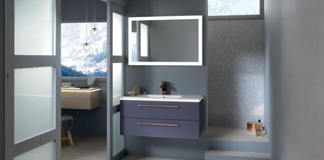 Salle de bains moderne avec meuble vasque suspendu, miroir lumineux et douche à l’italienne respectant les normes électriques.