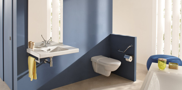 Salle de bains PMR avec lavabo suspendu et WC mural accessibles dans espace moderne.