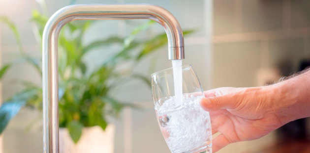 Personne qui se sert un verre d'eau à son robinet