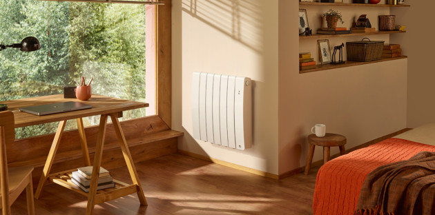 Radiateur électrique blanc positionné proche d'une fenêtre dans une chambre