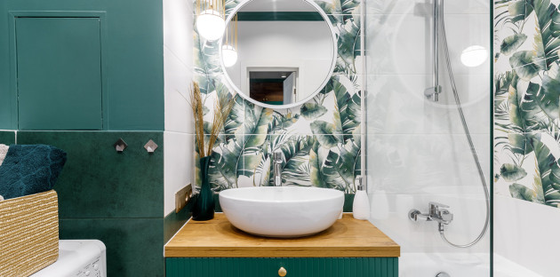 Petite salle de bains optimisée avec meuble vasque, miroir rond et carrelage végétal
