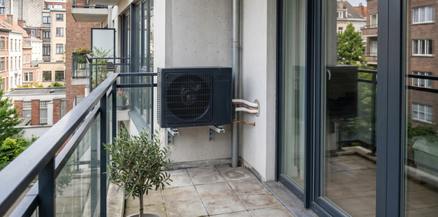 Unité extérieure de pompe à chaleur installée sur le balcon d’un appartement.