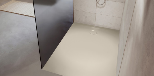 Receveur de douche extra-plat beige avec bonde centrale dans une douche moderne