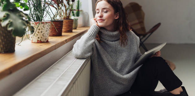 Femme en pull qui apprécie la chaleur dégagée par son radiateur