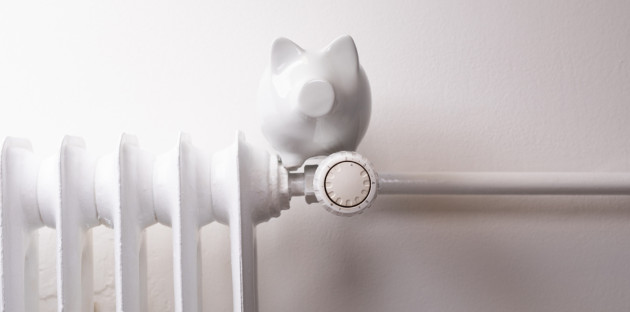 Radiateur blanc avec robinet thermostatique et tirelire posée au-dessus pour illustrer les économies de chauffage.