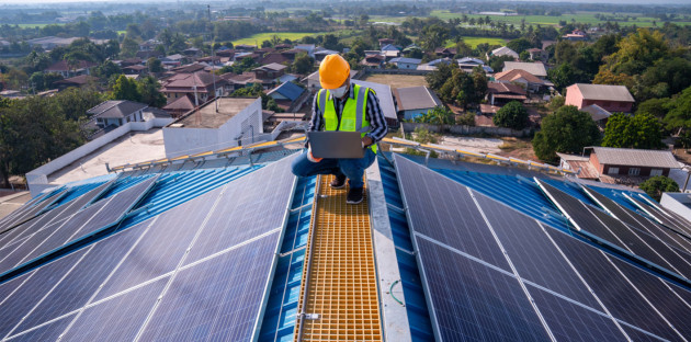 Ouvrier sur un toit qui utilise un ordinateur pour calculer le rendement d'une installation solaire