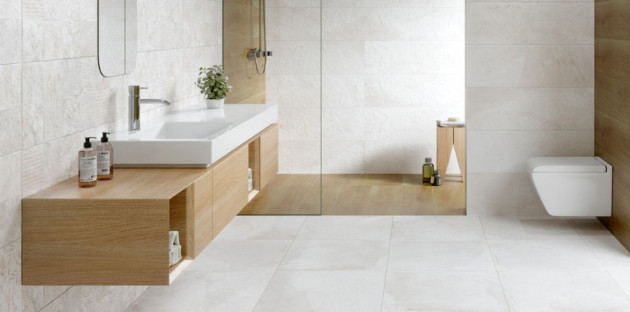 Salle de bains minimaliste avec meuble suspendu en bois clair, douche à l’italienne et WC suspendu.