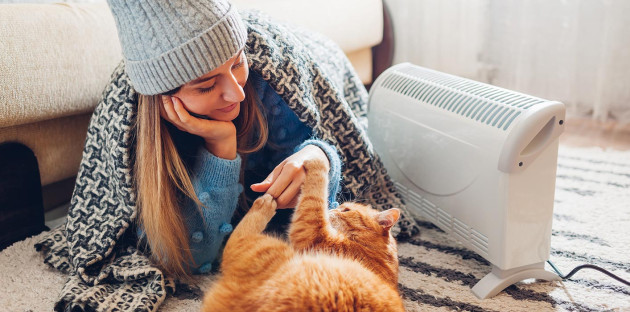 Femme en train de se détendre devant son chauffage d'appoint