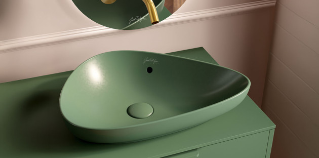 Vasque à poser verte mate au design organique installée sur un meuble coordonné.