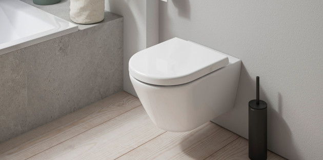 WC suspendu caréné blanc avec brosse WC noire, ambiance salle de bains moderne.