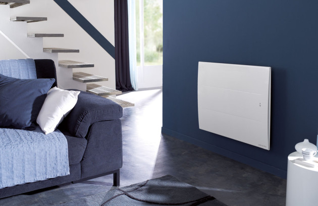 Radiateur rayonnant électrique fixé au mur dans une pièce de vie, chaleur infrarouge douce et diffusion homogène.