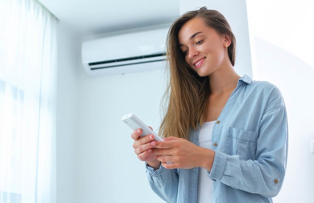 femme effectuant le réglage de sa climatisation avec une télécommande