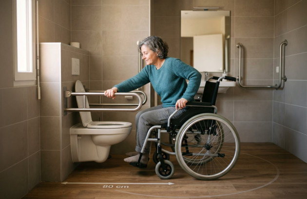 Personne en fauteuil roulant utilisant un WC adapté avec espace de transfert latéral