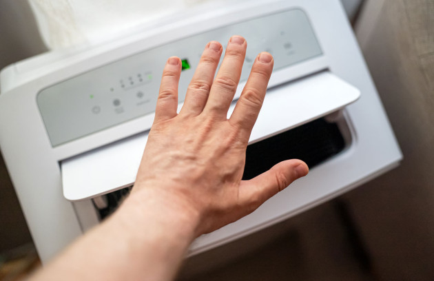 Main devant la sortie d’air d’un climatiseur monobloc