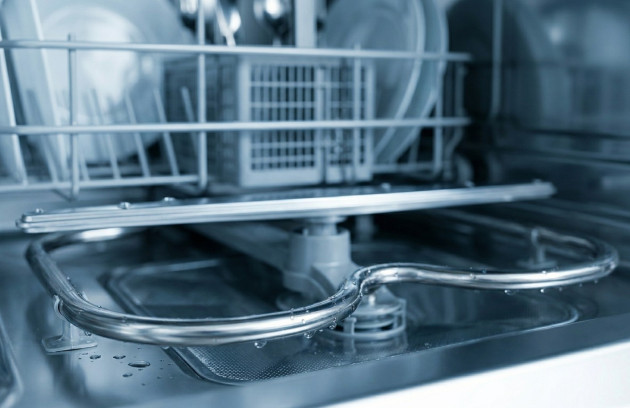 Intérieur de lave-vaisselle propre avec vaisselle rangée et bras de lavage visible.