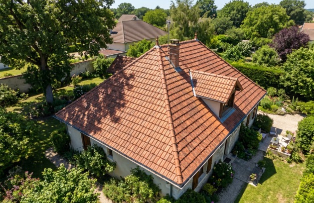 Vue aérienne d’une maison individuelle avec une grande toiture en tuiles.
