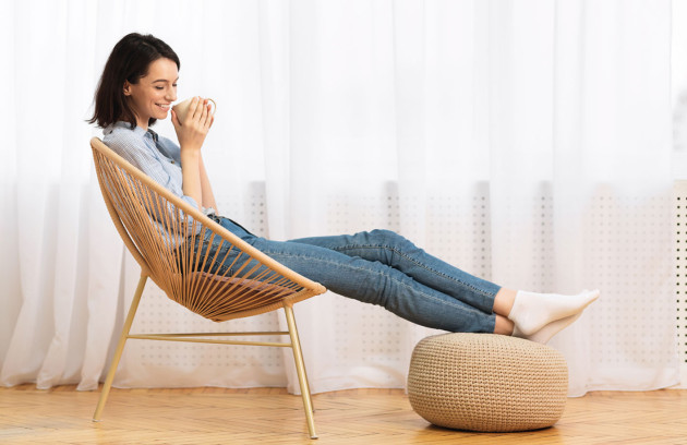 Femme se détendant près d’une fenêtre, illustrant le confort d’un radiateur rayonnant et sa chaleur infrarouge douce au quotidien.