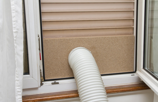 Tuyau d’évacuation d’air chaud d’un climatiseur mobile installé sur une fenêtre entrouverte.