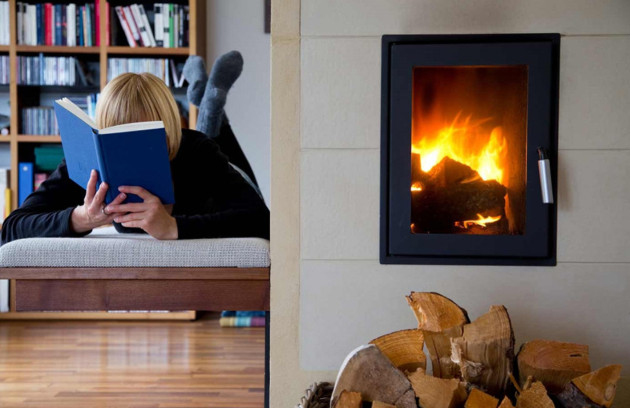 Lecture au coin du feu devant un poêle à bois encastré apportant chaleur et confort.