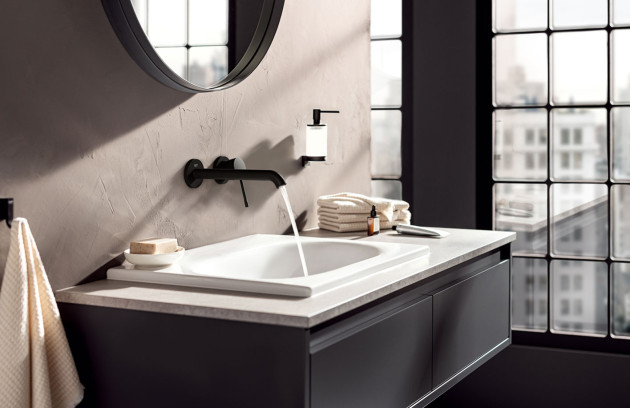 Robinet mural noir au-dessus d’un lavabo, salle de bains style industriel et lumière naturelle.