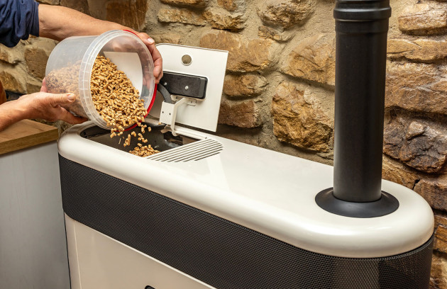 Tas de granulés de bois en vrac devant un poêle à pellets allumé apportant une chaleur douce