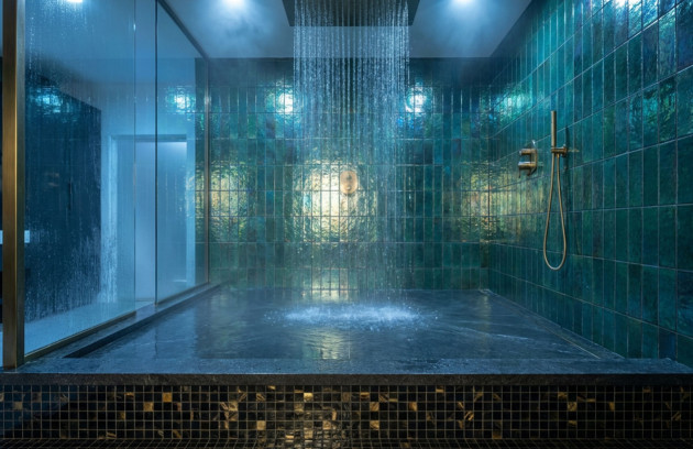 Douche à l’italienne avec carrelage mural vert brillant type zellige et mosaïque au sol, receveur intégré et paroi vitrée, illustrant le choix du carrelage et de la faïence en salle de bains humide.