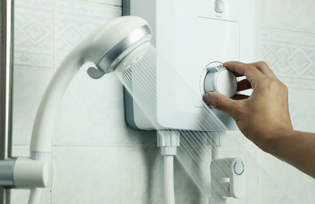 Chauffe-eau instantané électrique mural alimentant une douche, réglage de la température sur boîtier compact pour production d’eau chaude sanitaire à la demande.
