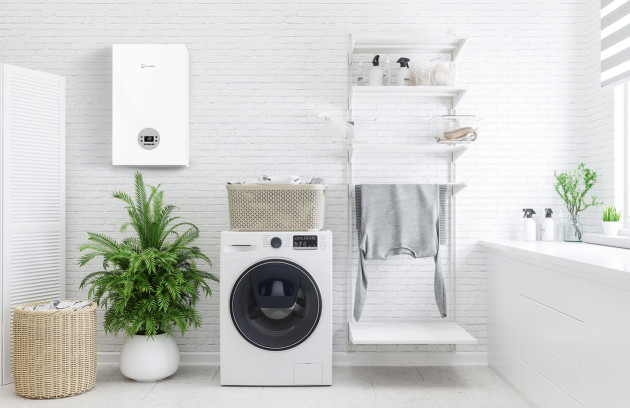 Chaudière gaz murale fixée dans une buanderie au-dessus d’un lave-linge