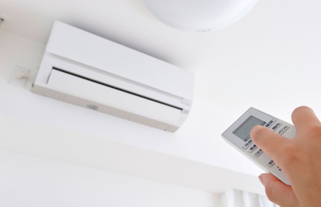 Climatiseur monobloc mural blanc installé en hauteur avec télécommande 