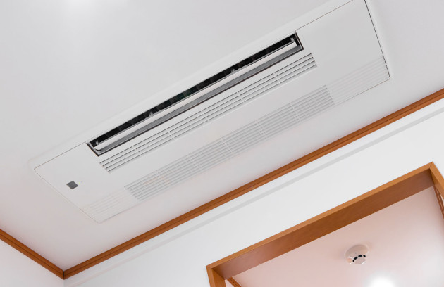 Grille de diffusion d’air d’une climatisation gainable dans un plafond de bureau, solution de climatisation invisible.