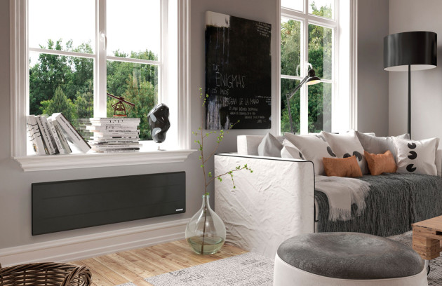 Radiateur rayonnant électrique noir installé sous une fenêtre dans un salon, panneau rayonnant diffusant une chaleur infrarouge homogène.