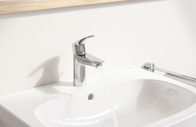 Mitigeur chromé sur lavabo blanc, jet d’eau et design épuré.