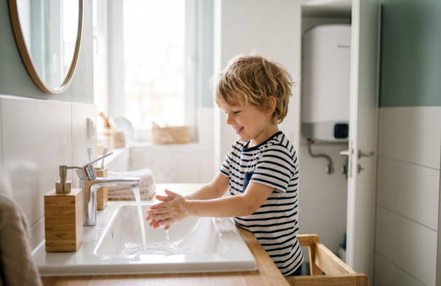 Enfant se lavant les mains dans une salle de bains équipée d’un chauffe-eau domestique