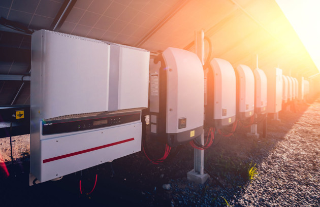 Ligne d'onduleurs solaires sous une installation de panneaux solaires au sol