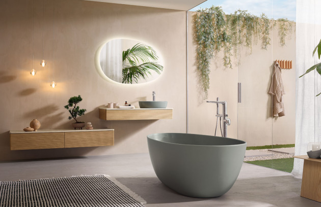 Salle de bains zen avec baignoire îlot verte, meuble bois flottant et miroir rond rétroéclairé, décoration végétale apaisante