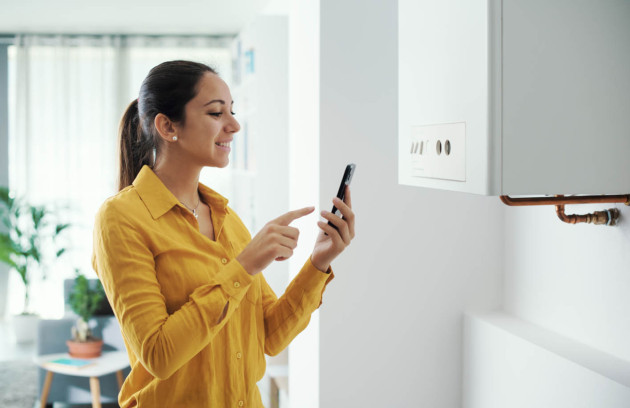 Utilisatrice pilotant sa chaudière connectée depuis une application mobile pour optimiser sa consommation énergétique
