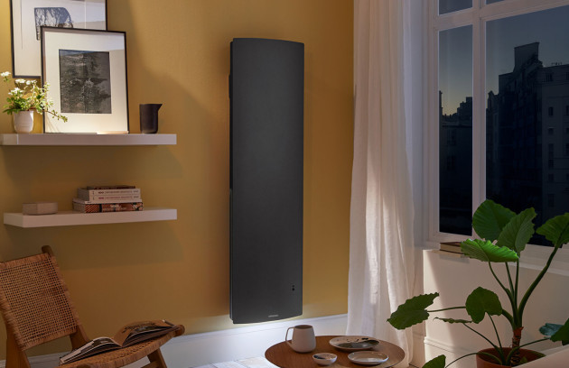 Radiateur rayonnant électrique vertical noir installé au mur dans un salon, chauffage par rayonnement infrarouge pour une montée en température rapide.