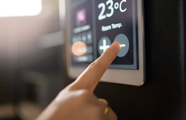 Réglage d’un thermostat digital de climatisation à 23 °C, doigt ajustant la température pour optimiser le confort thermique et réduire la consommation d’énergie du système de climatisation.