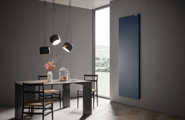 Radiateur rayonnant électrique vertical bleu dans une salle à manger moderne, chauffage par rayonnement infrarouge pour un confort rapide.