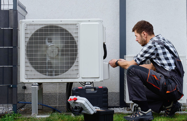 Technicien intervenant sur l’unité extérieure d’une climatisation réversible, installation ou maintenance.