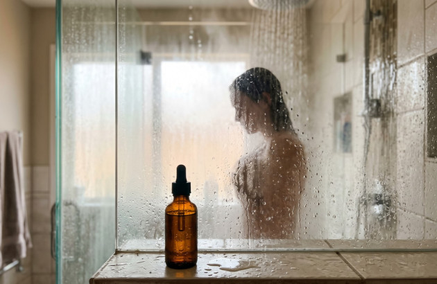 Douche avec flacon d’huile essentielle posé au premier plan pour une séance d’aromathérapie.