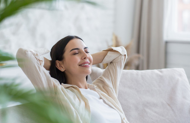 Femme détendue sur un canapé, illustrant le confort apporté par un climatiseur.