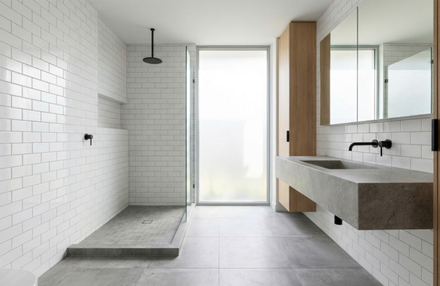 Salle de bains lumineuse avec faïence murale blanche type métro et carrelage gris au sol, douche à l’italienne et meuble vasque suspendu, illustrant le choix du carrelage et de la faïence.