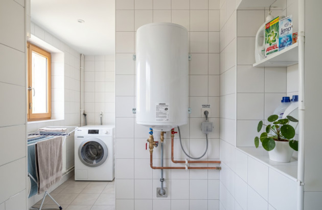 Chauffe-eau électrique installé dans une buanderie moderne avec raccordement apparent
